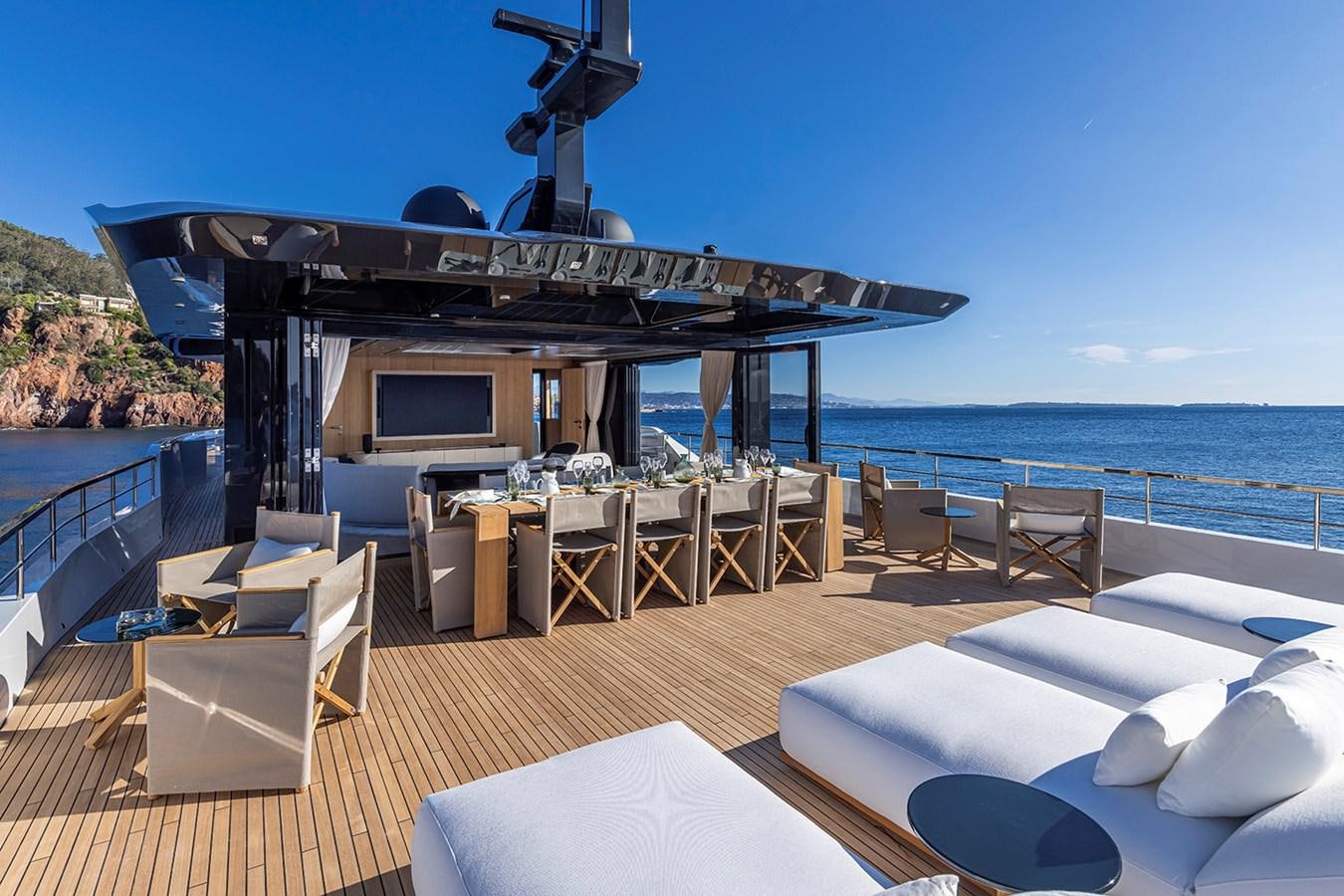 a deck with a table and chairs on it and a large body of water in the background aboard ARCADIA 96 Yacht for Sale
