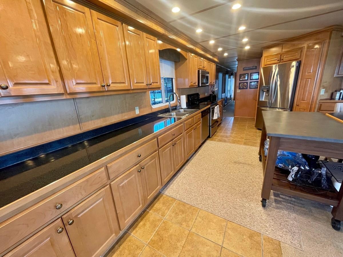a kitchen with wooden cabinets aboard 2005 HORIZON 18X88 HOUSEBOAT Yacht for Sale