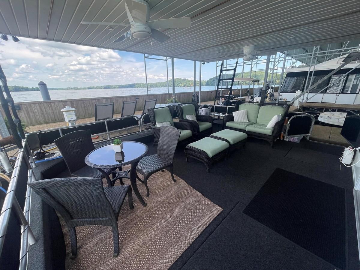 a room with a table chairs and a large window aboard 2005 HORIZON 18X88 HOUSEBOAT Yacht for Sale