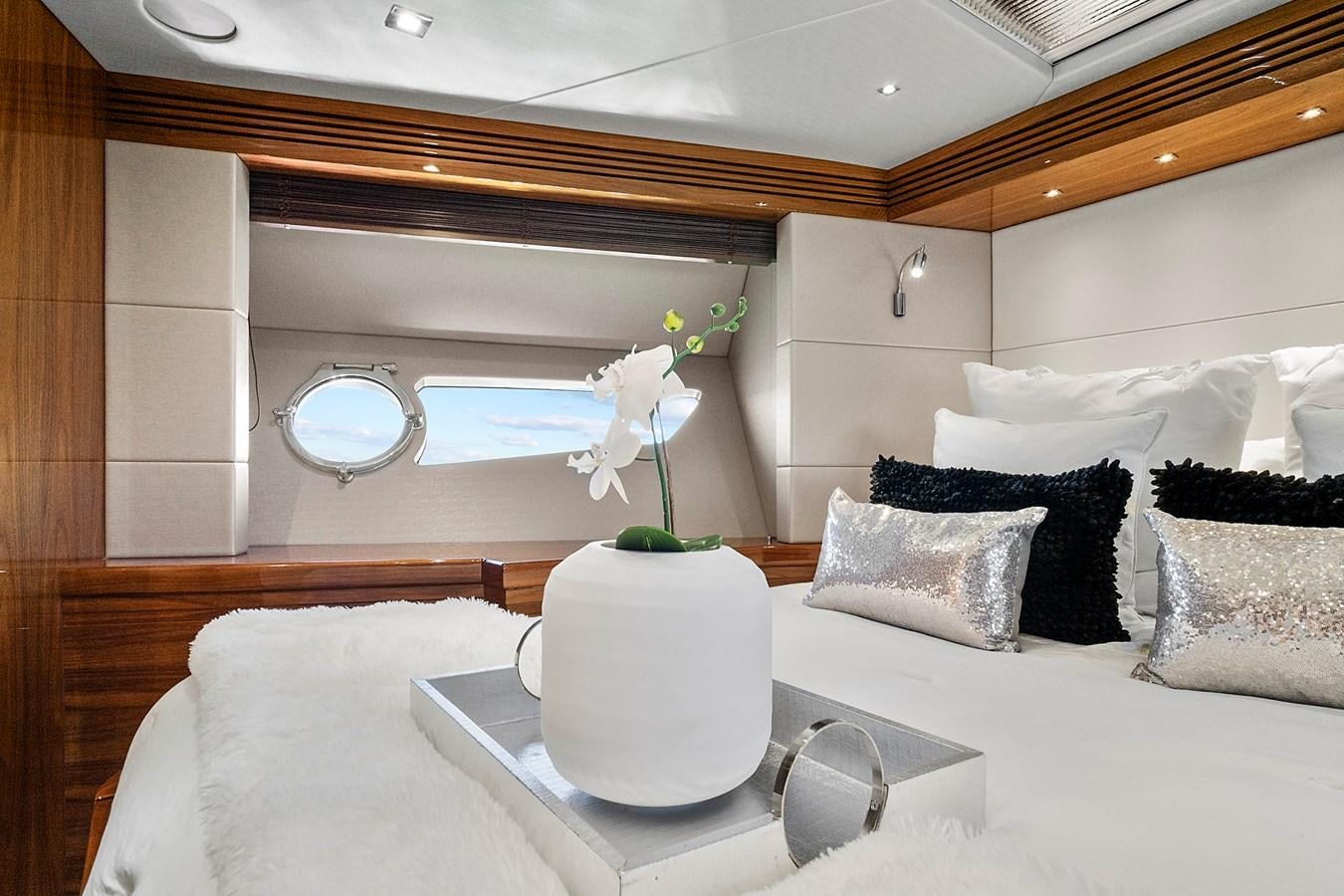 a white bed with pillows and a vase with flowers on it aboard KING Yacht for Sale