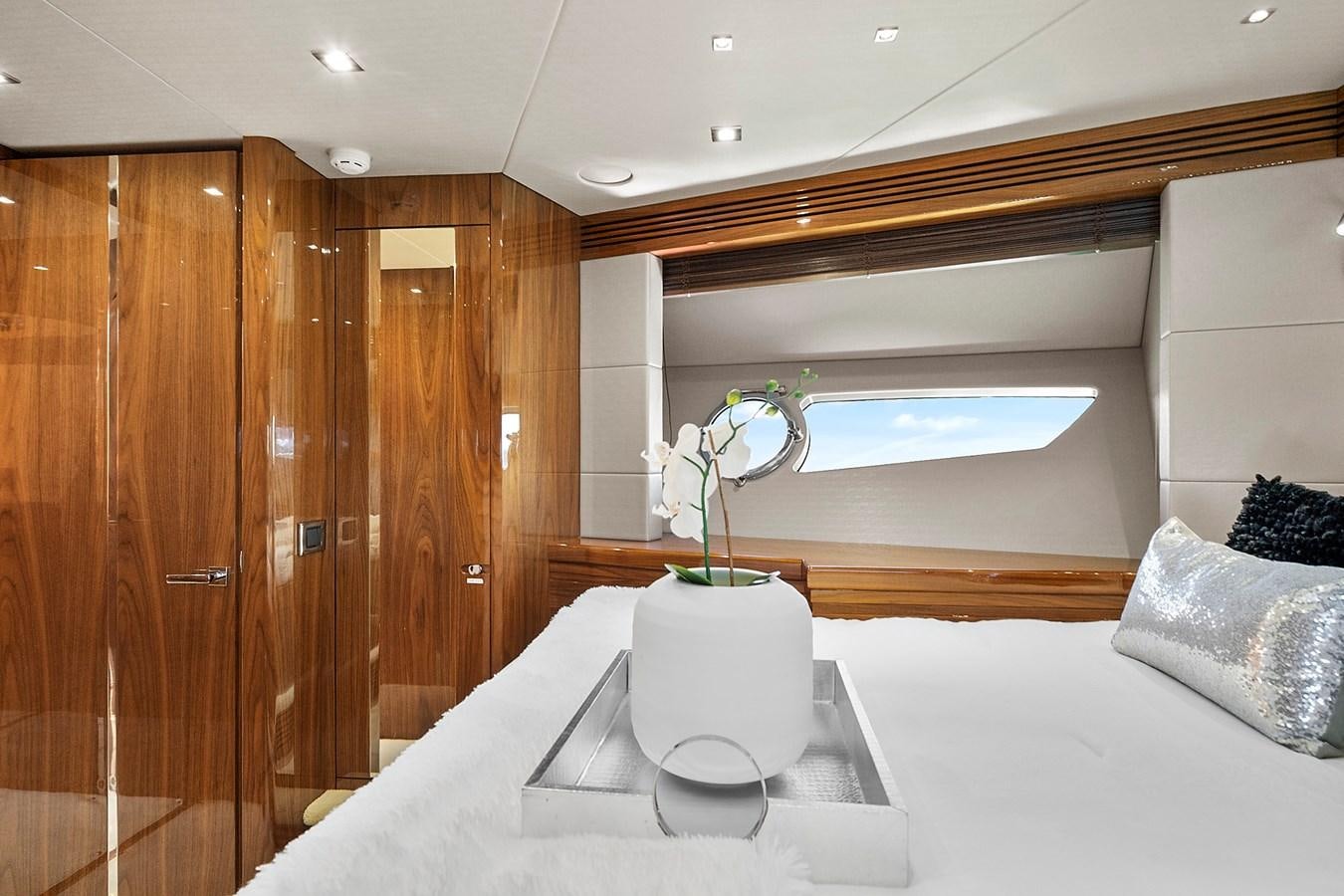 a white bed with a white pillow and a vase with flowers on it aboard KING Yacht for Sale