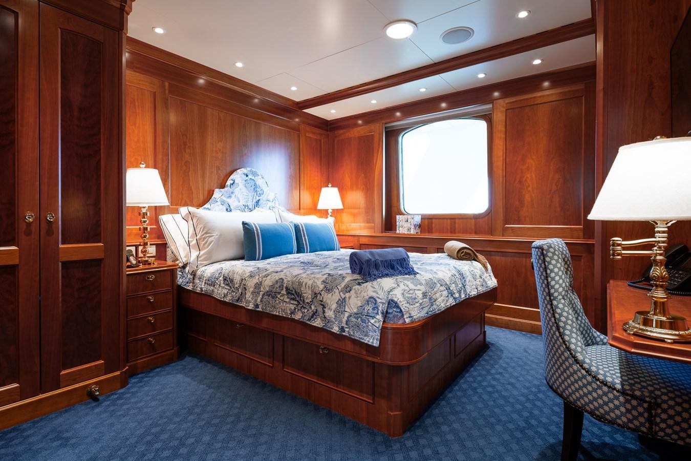 a bedroom with a bed and a chair aboard CUPANI Yacht for Sale
