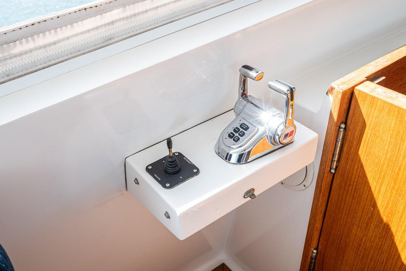 a white faucet on a white wall next to a wood cabinet aboard NIRVANA Yacht for Sale