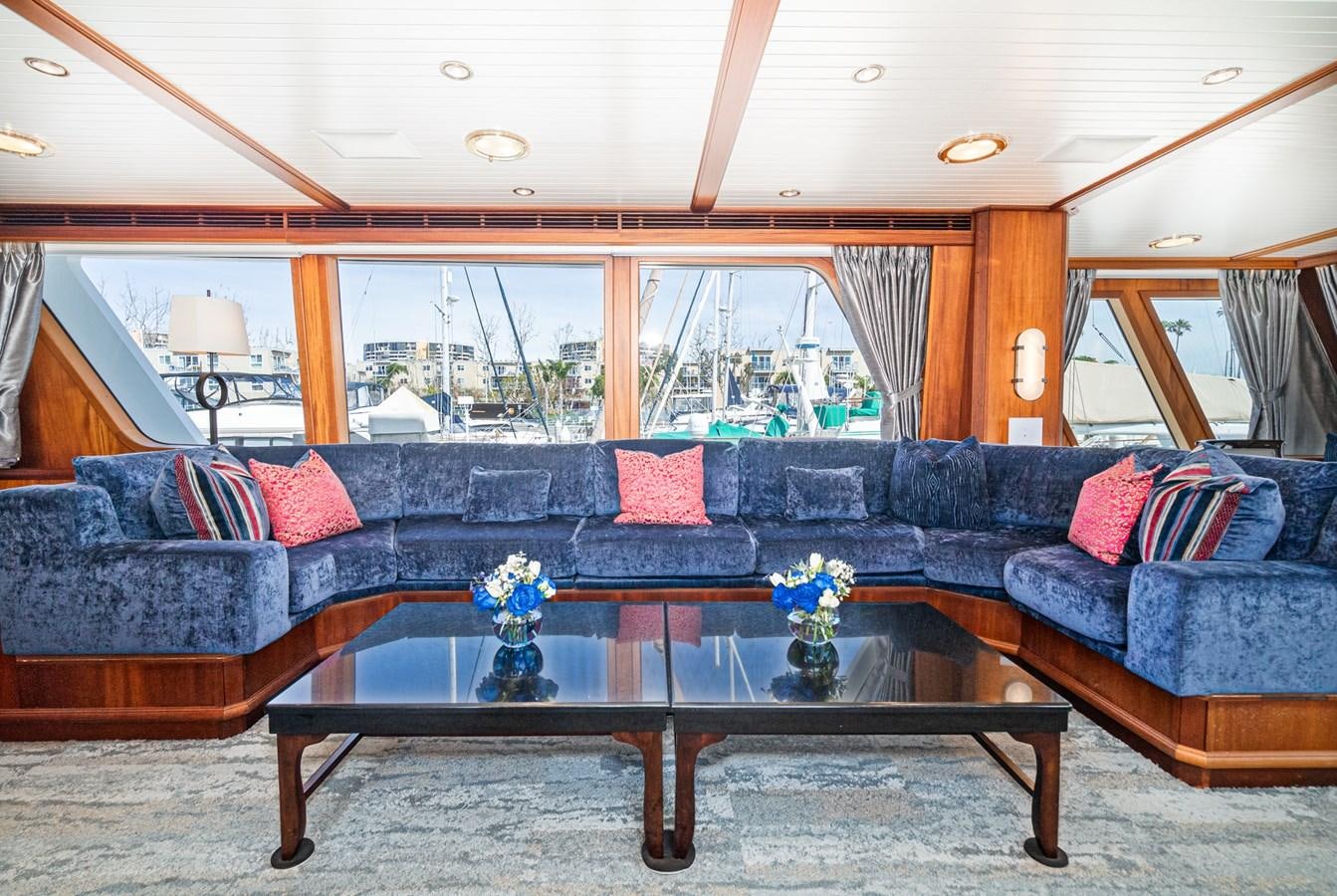 a living room with a large blue couch and a large window aboard NIRVANA Yacht for Sale