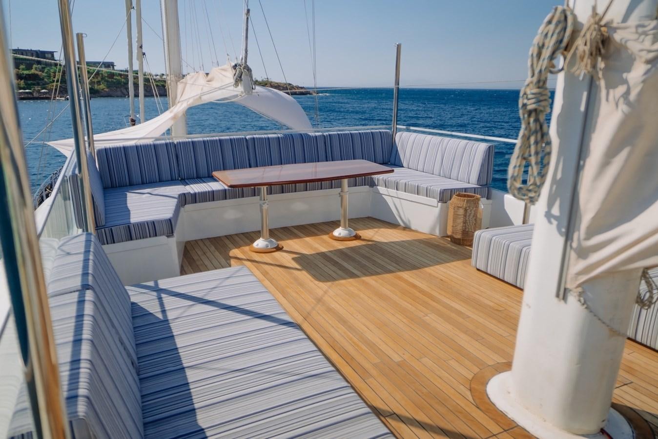 a deck with a table and chairs aboard CUSTOM MADE MOTORSAILER Yacht for Sale