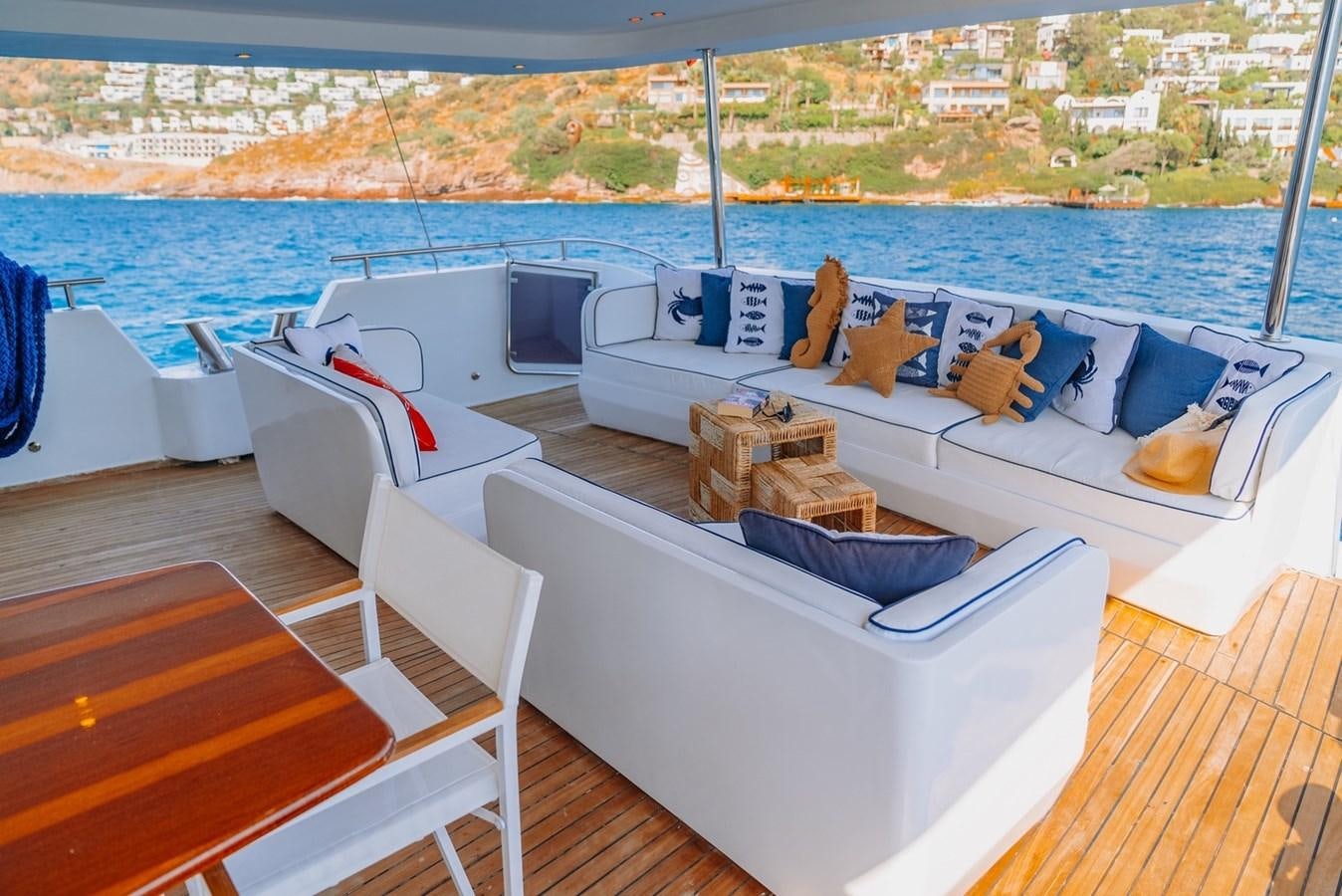 a room with a couch and a table with chairs on it aboard CUSTOM MADE MOTORSAILER Yacht for Sale