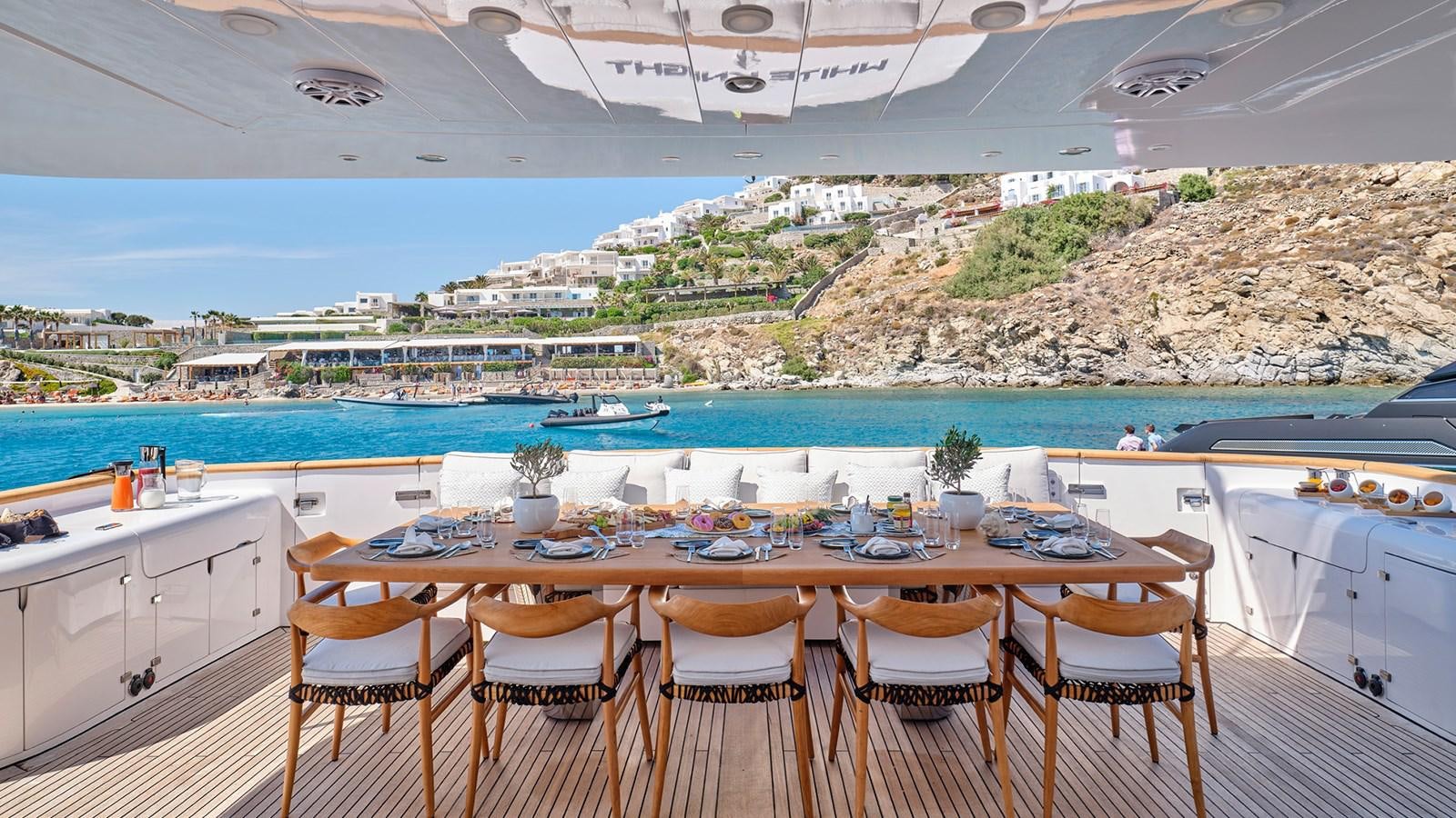 a table set for a meal on a balcony overlooking a beach aboard WHITE KNIGHT Yacht for Sale