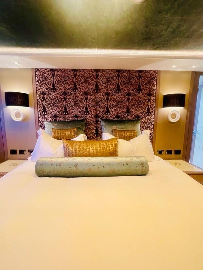a room with a bed and a wall with pink fabric and a painting on it aboard SKYE Yacht for Sale