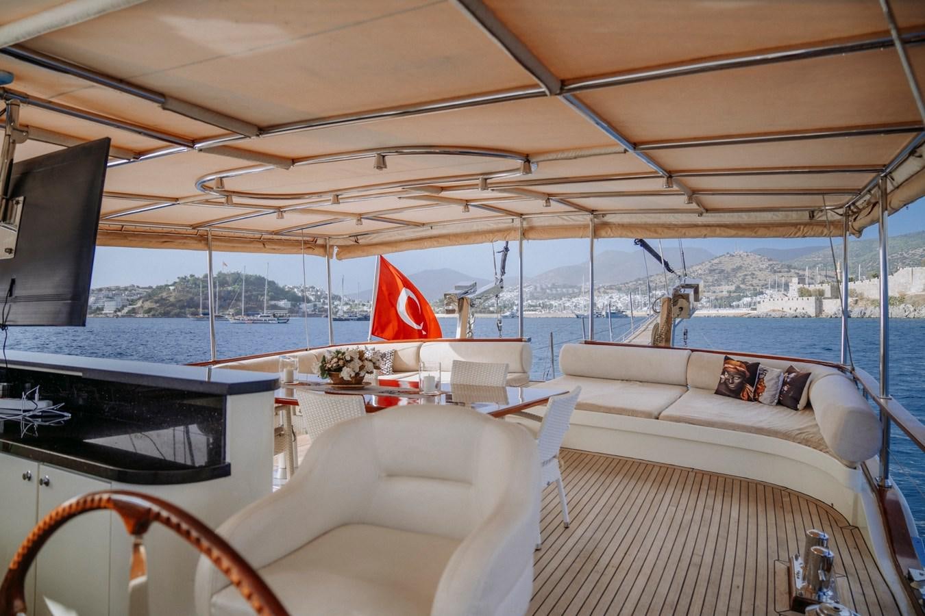a boat with a white couch and a red logo on the front aboard CUSTOM MADE MOTORSAILER Yacht for Sale