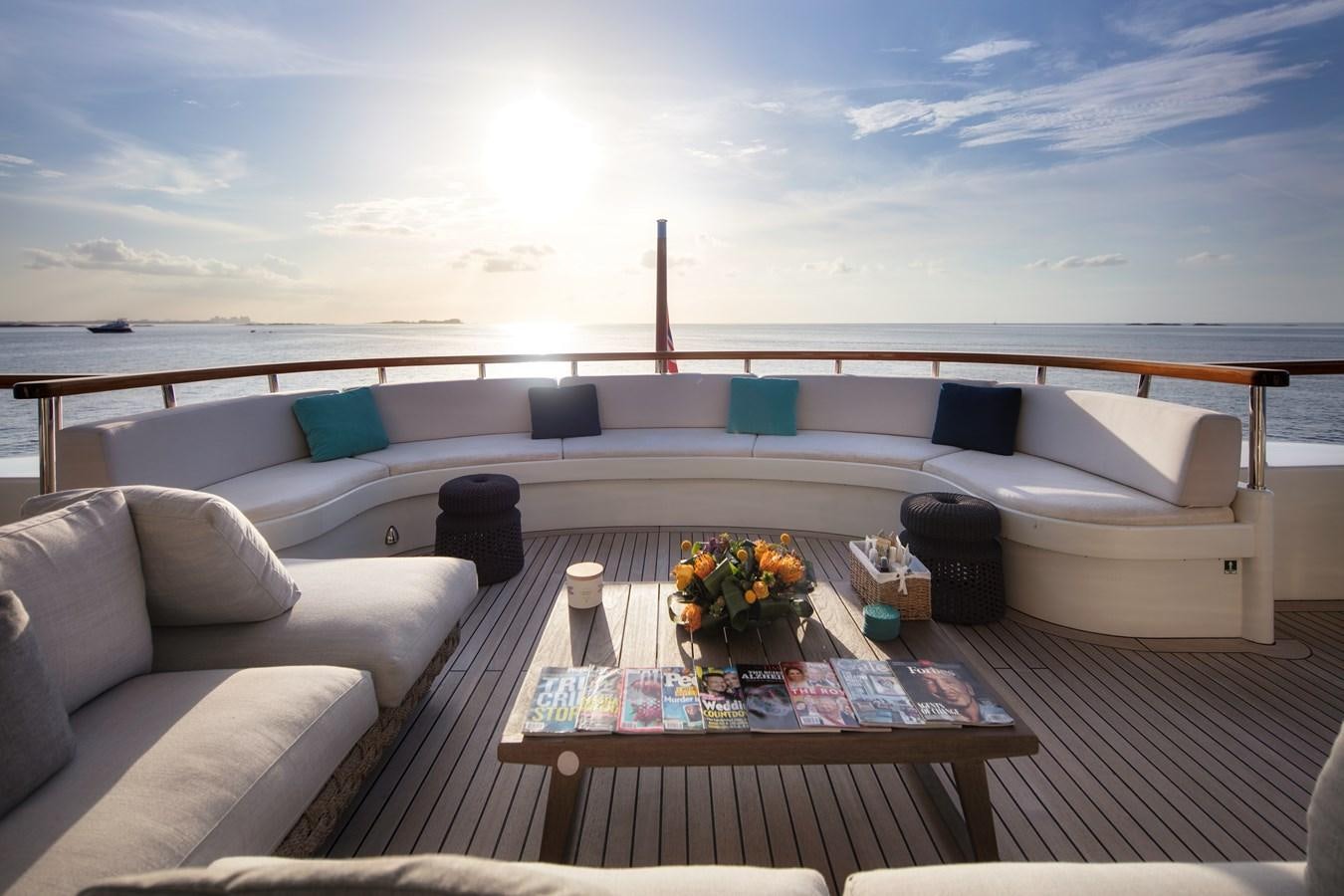 a couch and a table on a deck overlooking a beach aboard MYSTIC Yacht for Sale