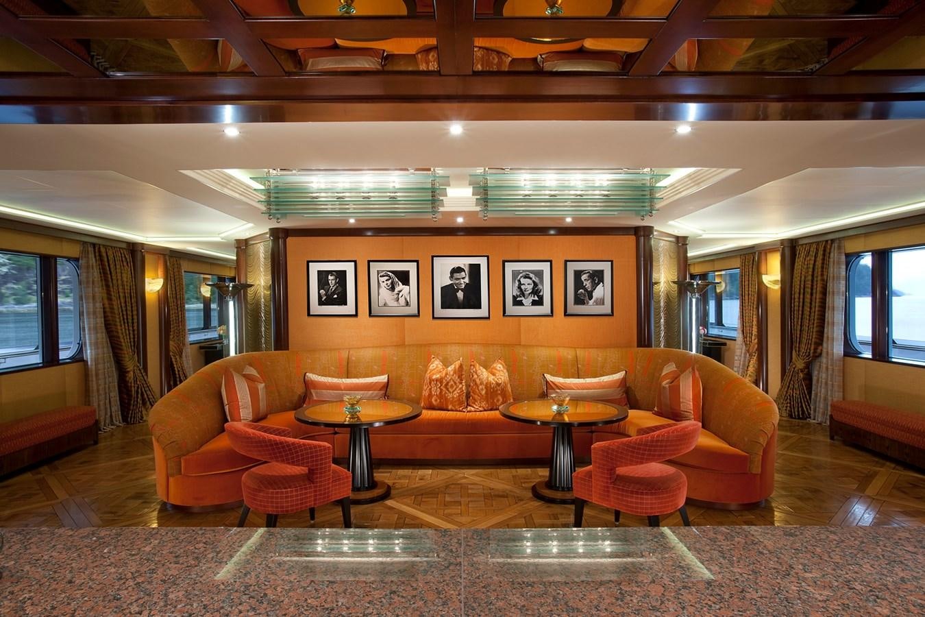 a room with orange couches and a table aboard ATTESSA IV Yacht for Sale