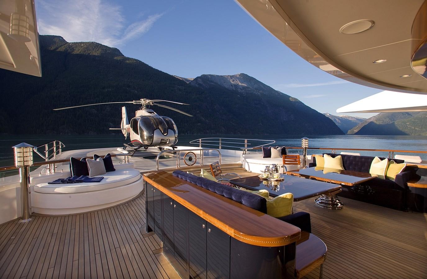 a room with a large white ship on the deck and a large body of water and mountains in aboard ATTESSA IV Yacht for Sale