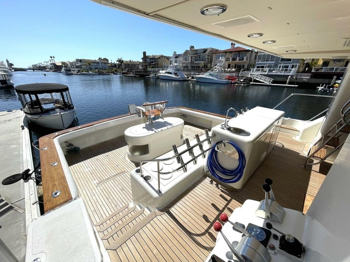 a deck with a boat and a table on it aboard AFTER MIDNIGHT Yacht for Sale