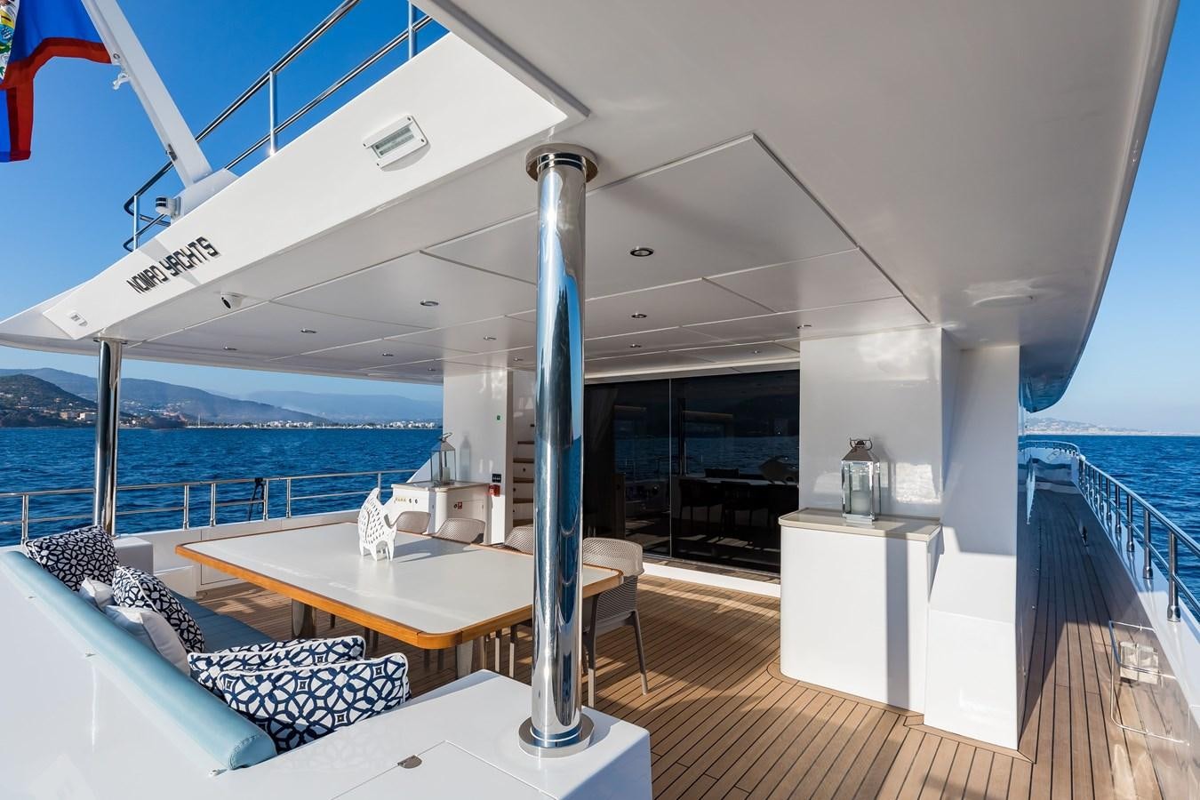 a large white room with a table and chairs aboard NOMAD 95 SUV Yacht for Sale