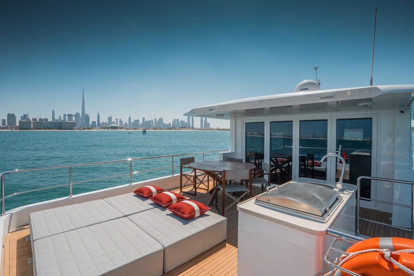 a balcony with a table and chairs on it and a city in the background aboard #4 NOMAD 75 SUV Yacht for Sale