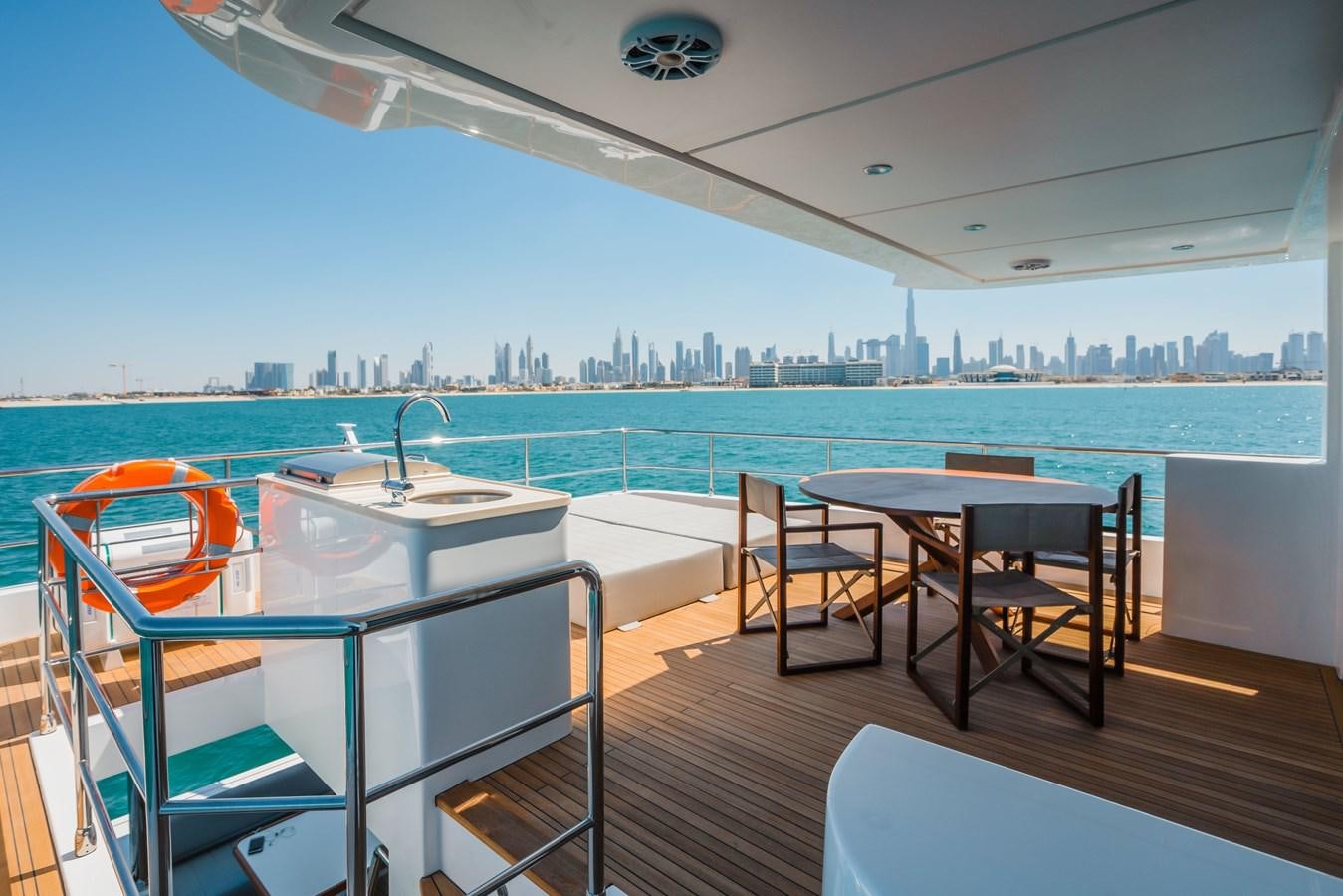 a balcony with a table and chairs on a deck overlooking a city aboard #4 NOMAD 75 SUV Yacht for Sale