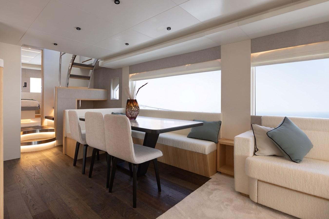 a living room with a table and couches aboard NOMAD 70 SUV Yacht for Sale