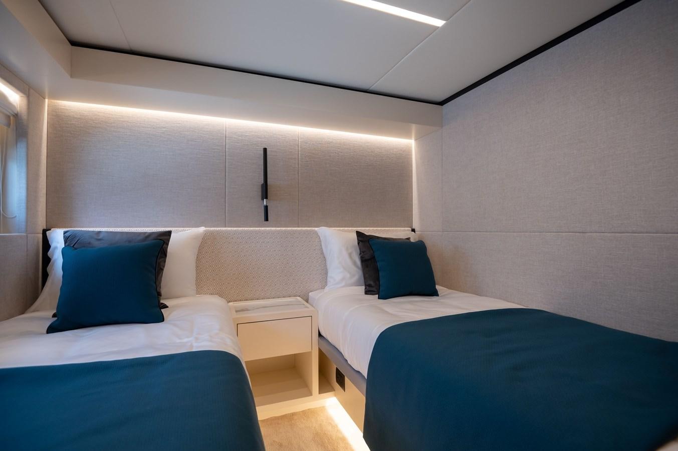 a room with beds and a blue couch aboard NOMAD 70 SUV Yacht for Sale