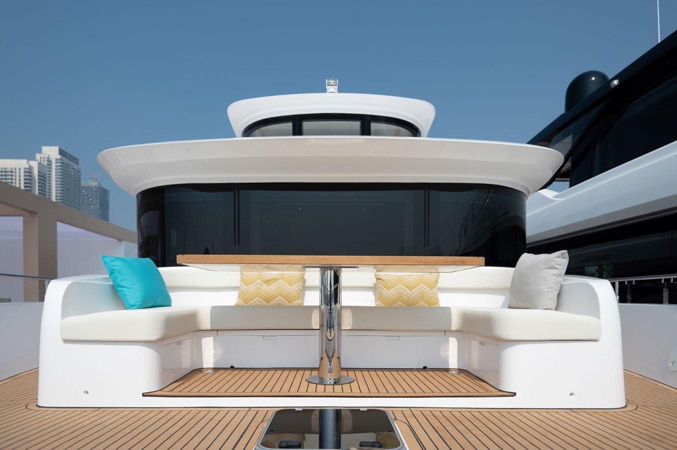 a white couch with a black and white striped pillow in front of a black car aboard NOMAD 70 SUV Yacht for Sale