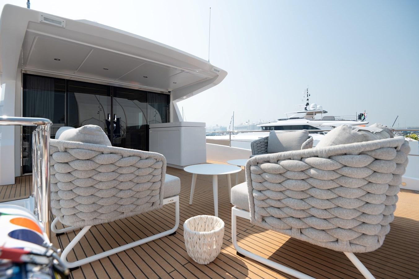 a table with chairs and a white chair on it aboard NOMAD 70 SUV Yacht for Sale