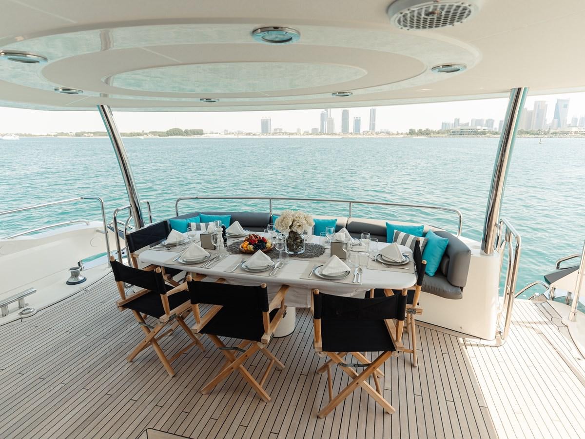 a table set for a dinner on a deck overlooking a large body of water aboard AARNA Yacht for Sale