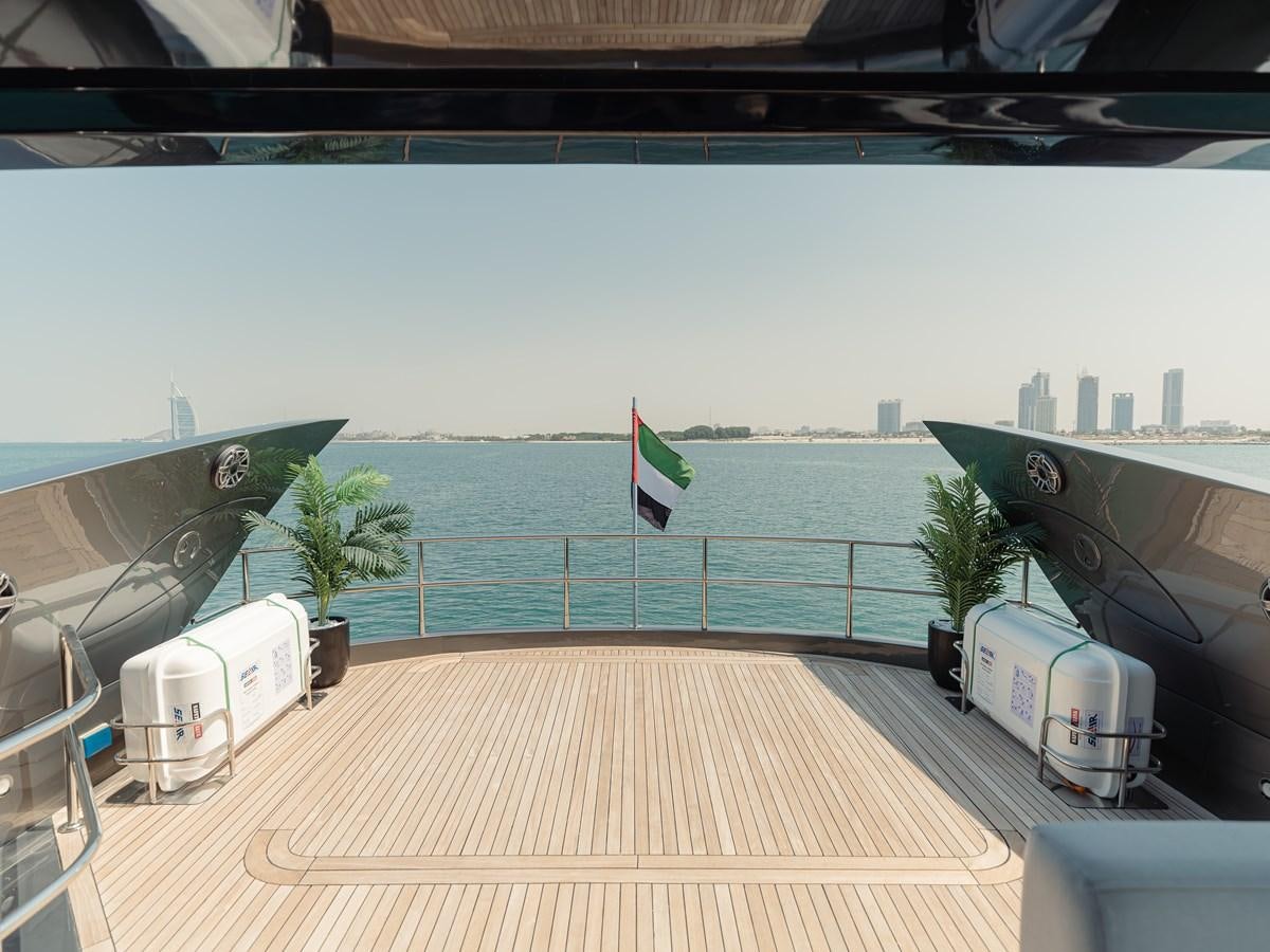a deck with a flag and a city in the background aboard MATRIX Yacht for Sale