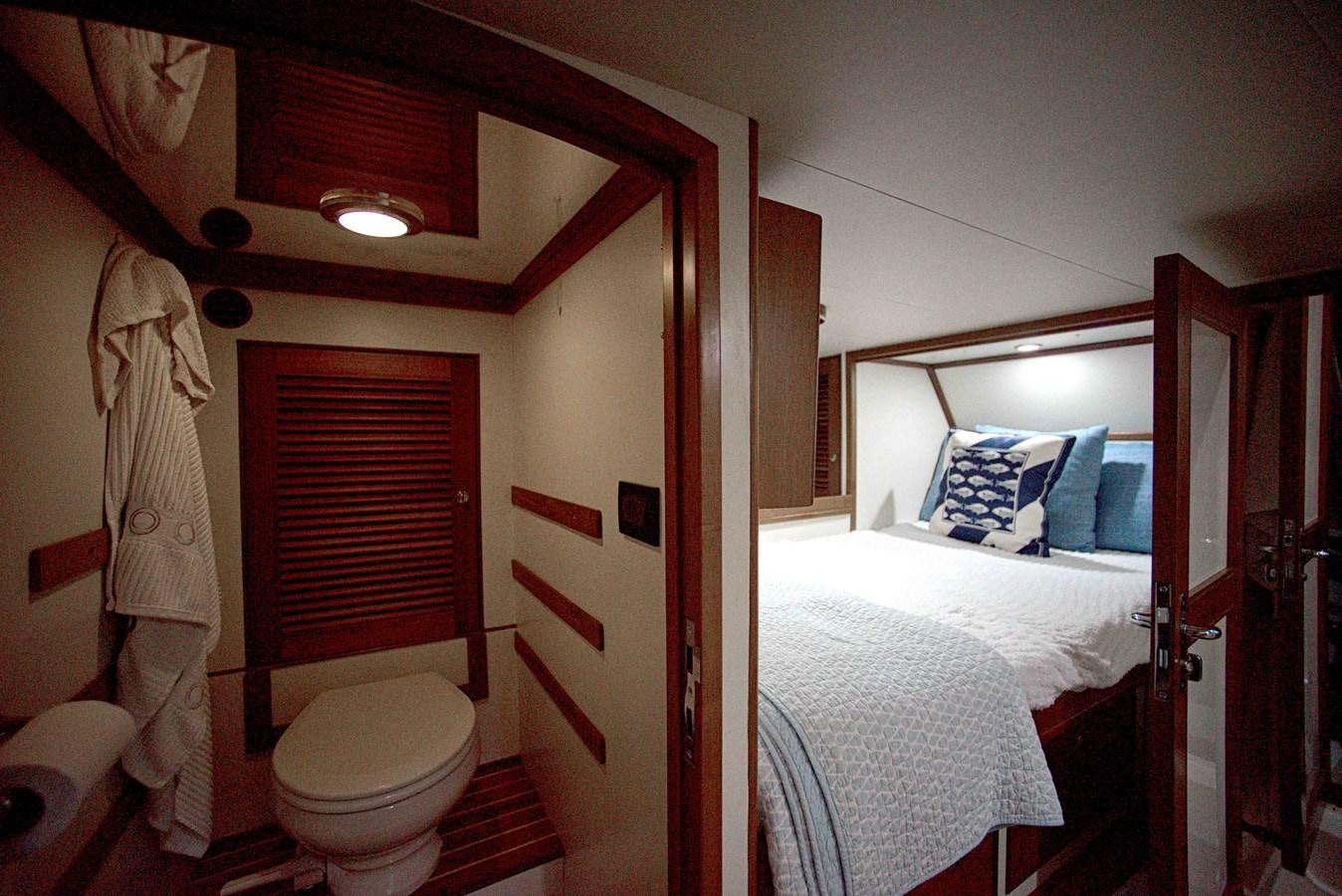 a bedroom with a bed and a mirror aboard RODE RUNNER II Yacht for Sale