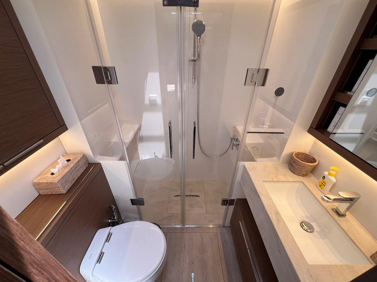 a bathroom with a shower sink and a toilet aboard 2023 LAGOON 67 Yacht for Sale