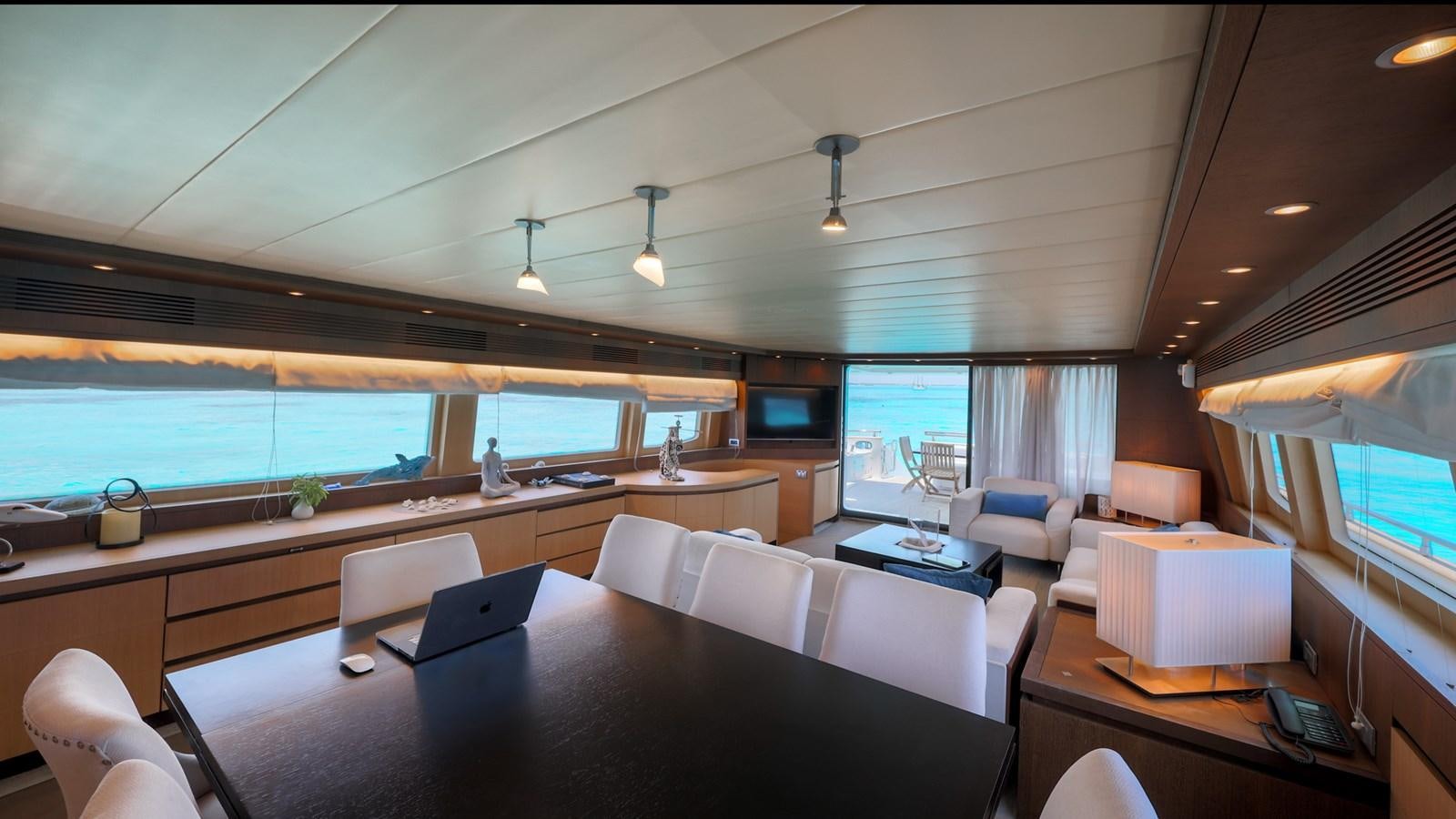 a room with a large window and a table with chairs and a view of the water aboard DOMINIC  2008 MAIORA 27M @ PUERTO AVENTURAS Yacht for Sale