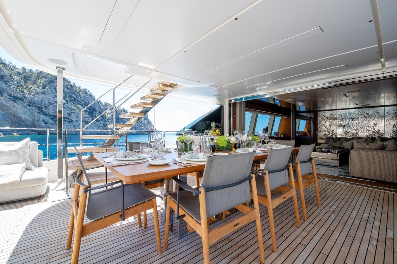 a deck with a table and chairs on it aboard MAC ONE Yacht for Sale