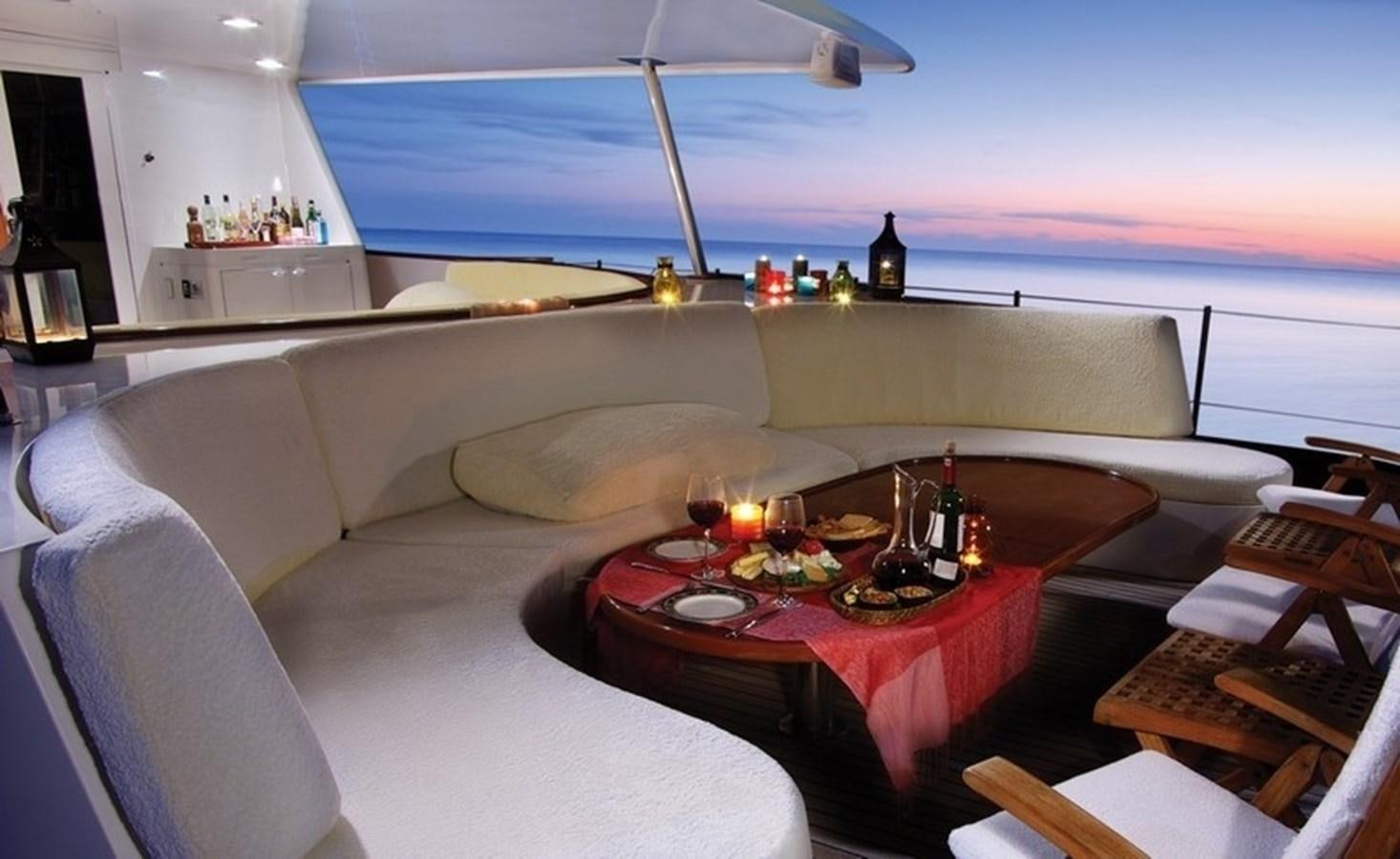 a large living room with a large sofa and a table with food on it aboard HAPPY Yacht for Sale