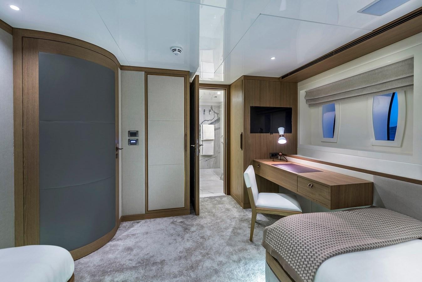 a bedroom with a bed and desk aboard LIQUID SKY Yacht for Sale