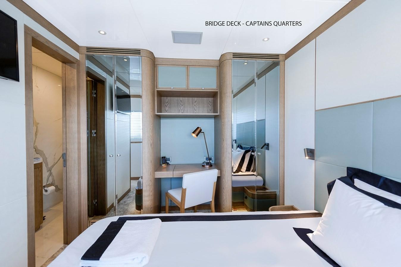 a bedroom with a bed and a desk aboard LIQUID SKY Yacht for Sale