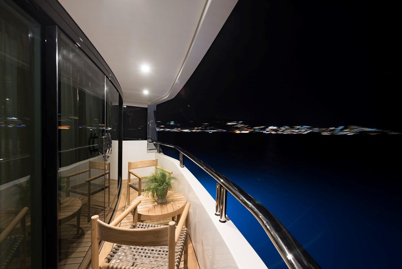 a balcony with a view of a city at night aboard LIQUID SKY Yacht for Sale