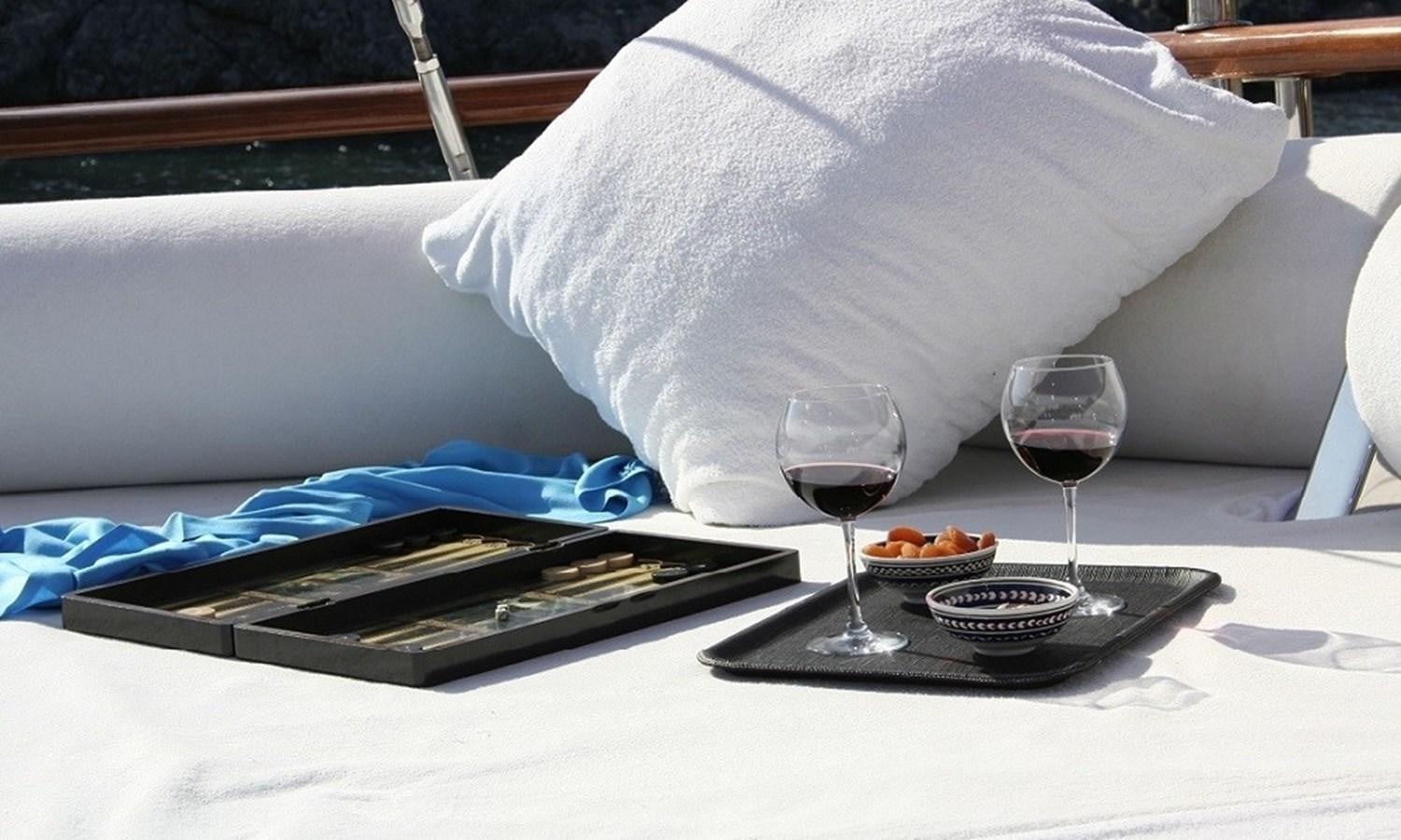 a tray of food and a glass of wine on a table aboard ATALANTE Yacht for Sale