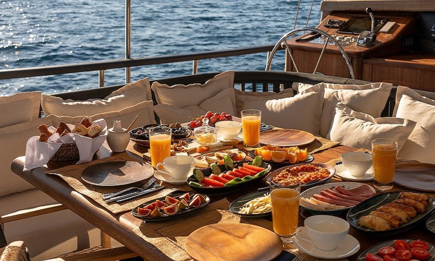 a table with food and drinks on it aboard CUSTOM MADE MOTORSAILOR Yacht for Sale