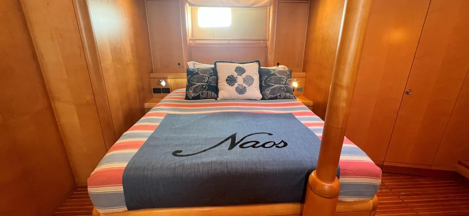 a bed with a blue and white striped pillow and a black and white striped pillow on it aboard NAOS Yacht for Sale