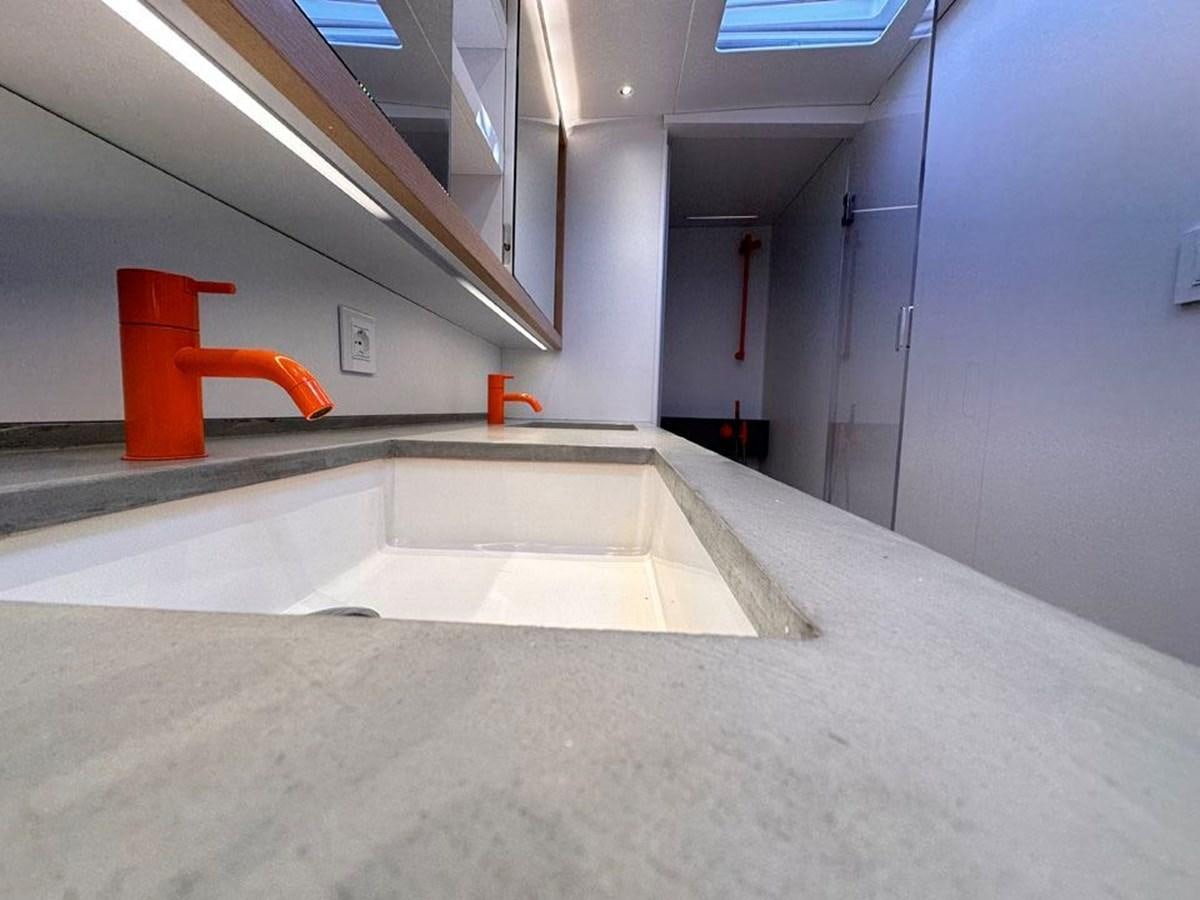 a long white room with a red chair aboard KARMA Yacht for Sale