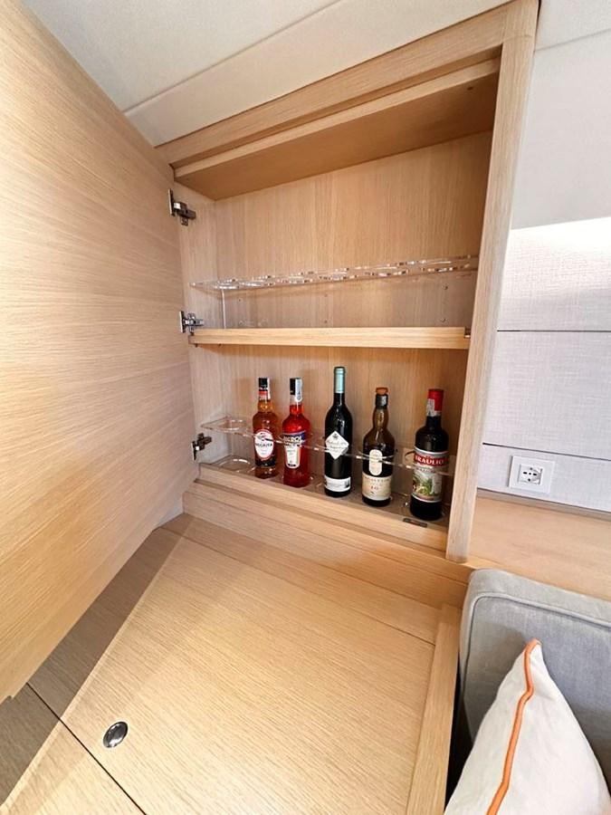 a wooden cabinet with bottles of wine aboard KARMA Yacht for Sale