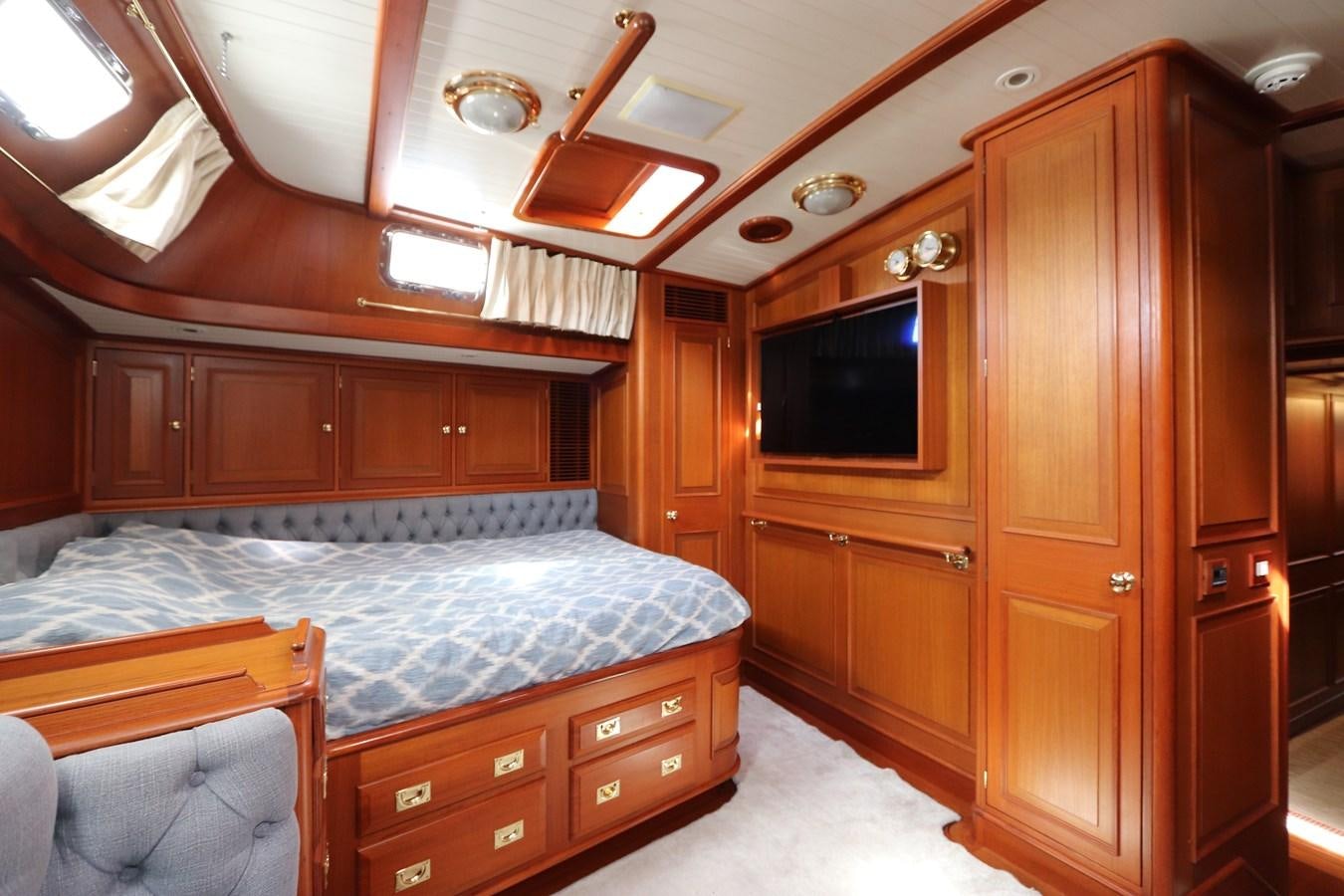 a bedroom with a bed and a wood cabinet aboard KEEWAYDIN Yacht for Sale
