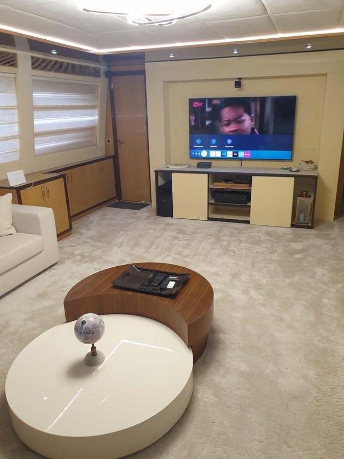 a living room with a tv and a table aboard NIKE III Yacht for Sale
