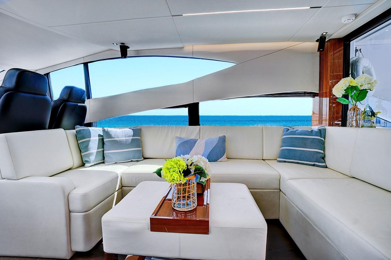 a white living room with a large blue and white sofa and a table with a vase of flowers aboard ONCE AROUND Yacht for Sale