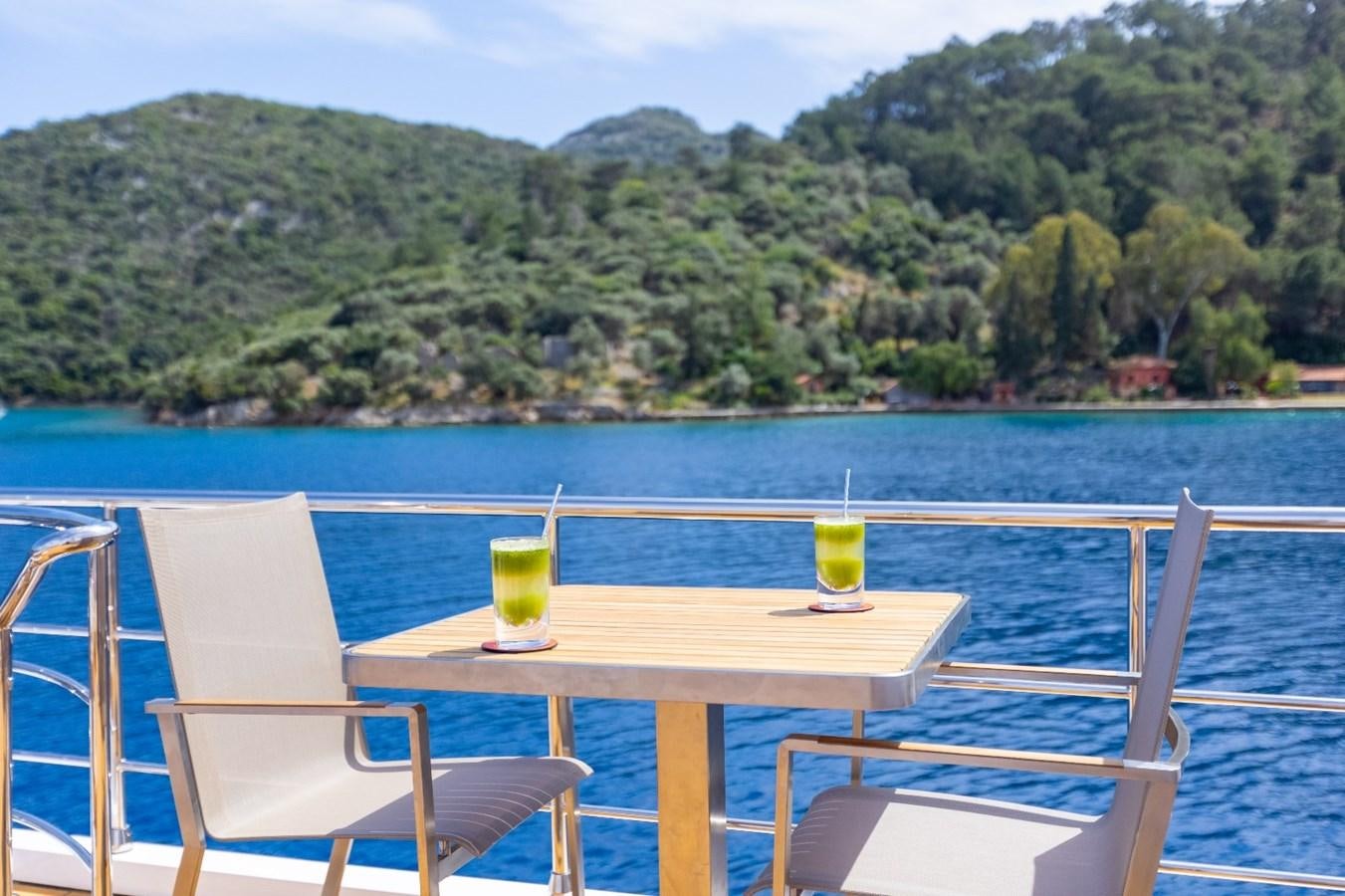 a table and chairs on a deck overlooking a body of water aboard AFRICA ONE Yacht for Sale