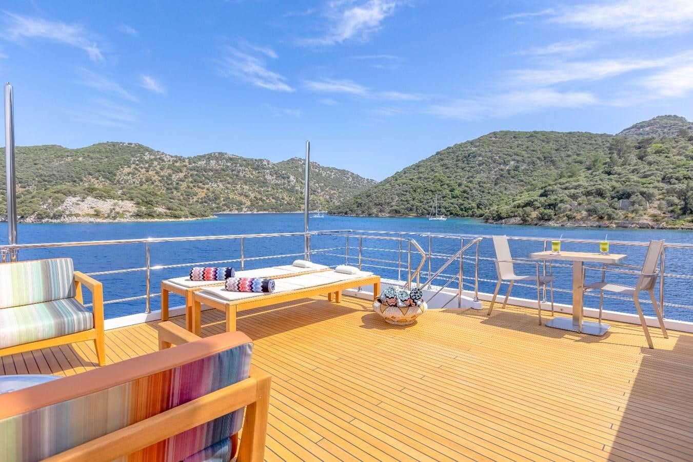 a deck with a table and chairs on it by the water aboard AFRICA ONE Yacht for Sale