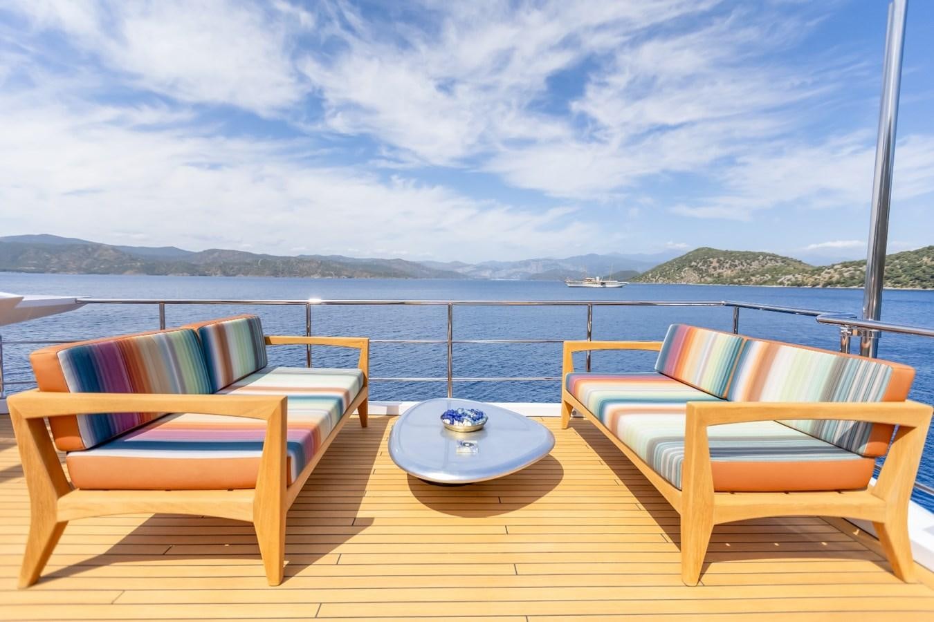 a table and chairs on a deck overlooking a body of water aboard AFRICA ONE Yacht for Sale