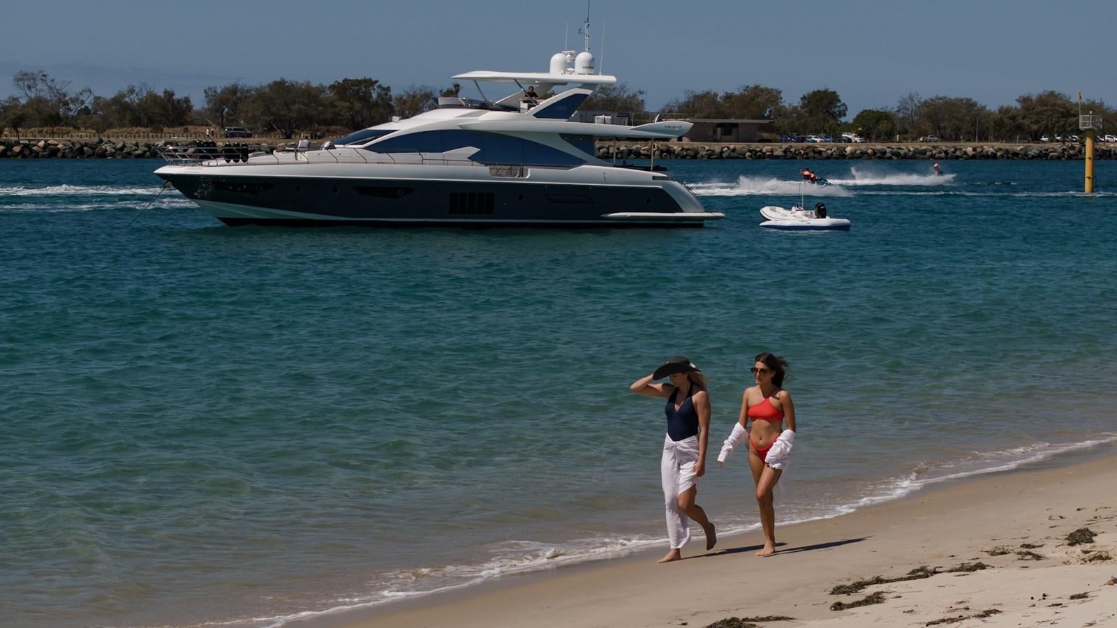 a couple of people on a beach by a large boat aboard SOLACE Yacht for Sale