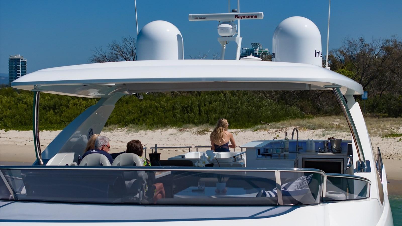 a group of people sitting in a convertible car on a road with a white tent and trees and aboard SOLACE Yacht for Sale