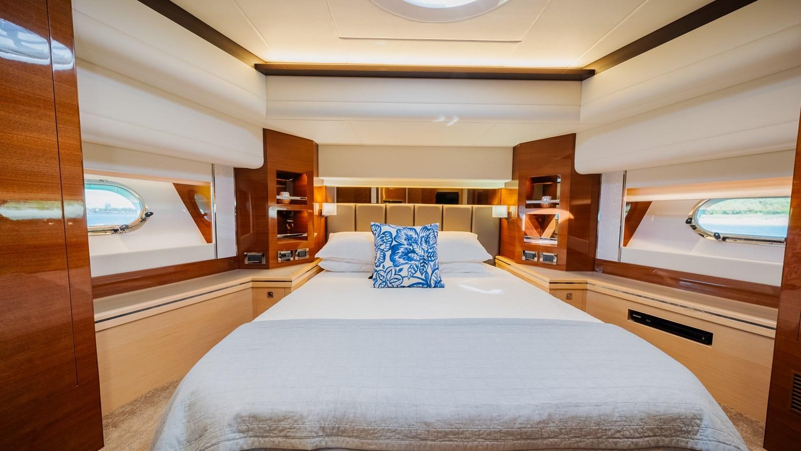 a bed with a white sheet and pillows in a room with a window aboard OHANA Yacht for Sale