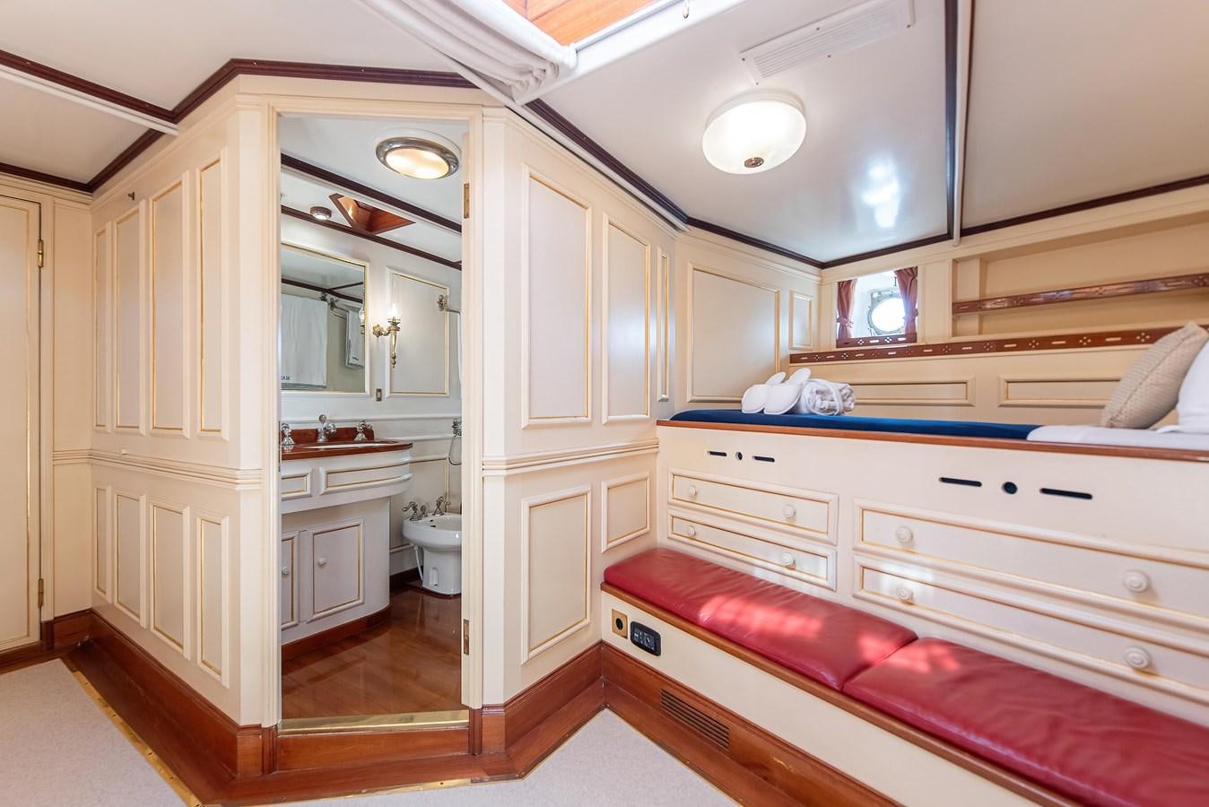 a bathroom with a red bed and white cabinets aboard MARIETTE OF 1915 Yacht for Sale