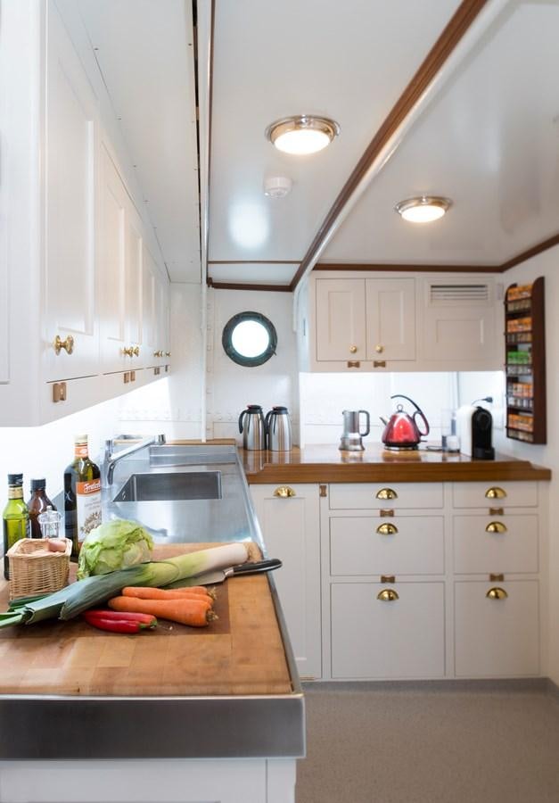 a kitchen with white cabinets aboard MARIETTE OF 1915 Yacht for Sale